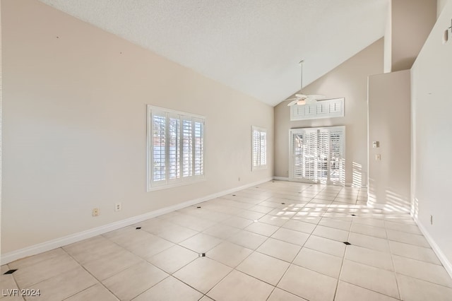 unfurnished living room with a textured ceiling, ceiling fan, high vaulted ceiling, and light tile patterned floors