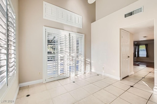 unfurnished room featuring a towering ceiling and light tile patterned flooring