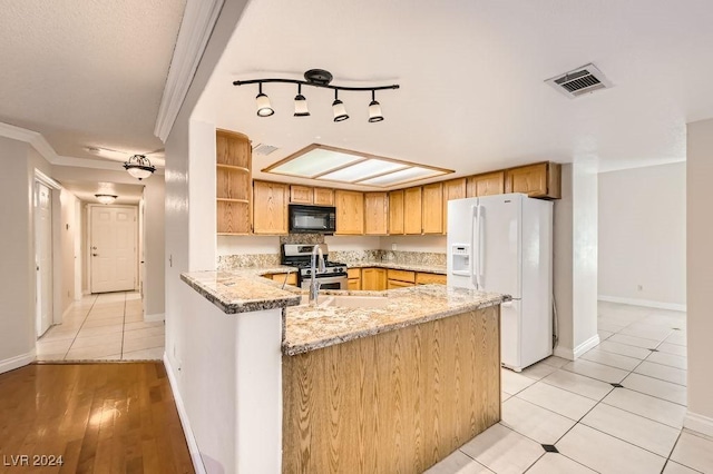 kitchen with kitchen peninsula, light stone counters, stainless steel gas stove, light hardwood / wood-style floors, and white fridge with ice dispenser