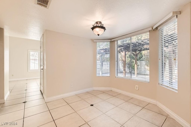 unfurnished room with light tile patterned flooring and a textured ceiling