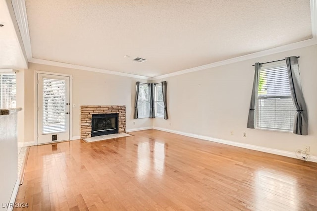 unfurnished living room featuring a textured ceiling, ornamental molding, a fireplace, and light hardwood / wood-style flooring