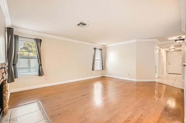 unfurnished room featuring a stone fireplace, crown molding, and light wood-type flooring