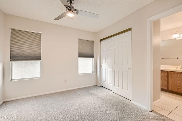 unfurnished bedroom with connected bathroom, ceiling fan, light colored carpet, a textured ceiling, and a closet