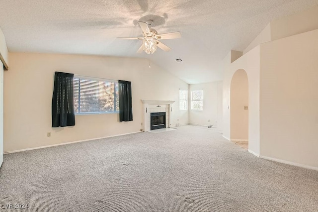 unfurnished living room featuring light colored carpet, ceiling fan, lofted ceiling, and a tiled fireplace