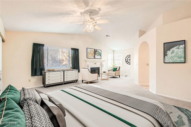 carpeted bedroom featuring ceiling fan, a fireplace, and vaulted ceiling