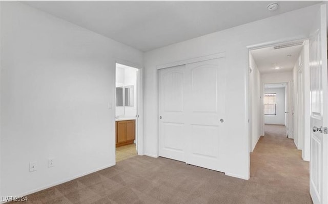 unfurnished bedroom featuring a closet, connected bathroom, and carpet