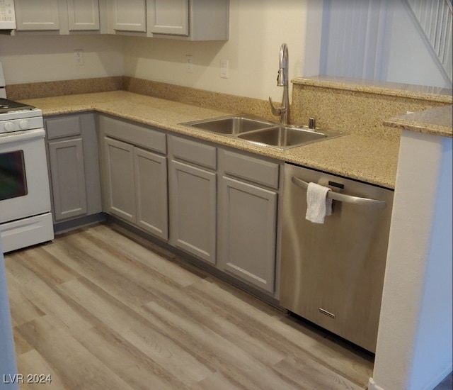 kitchen with gray cabinets, sink, light wood-type flooring, and white appliances