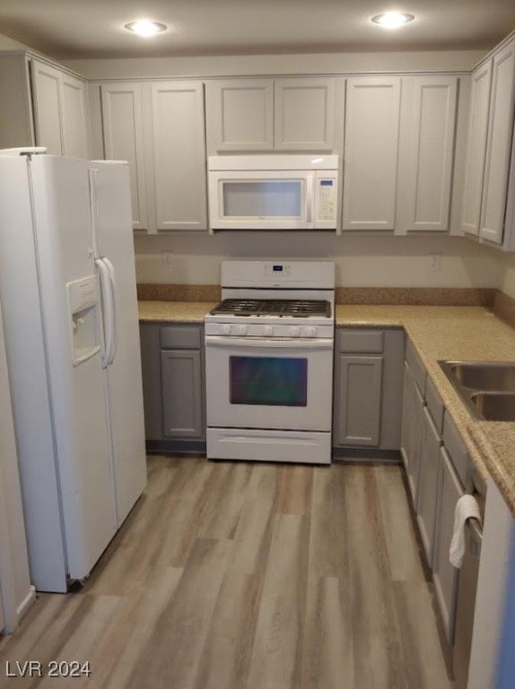 kitchen with white cabinets, light wood-type flooring, and white appliances