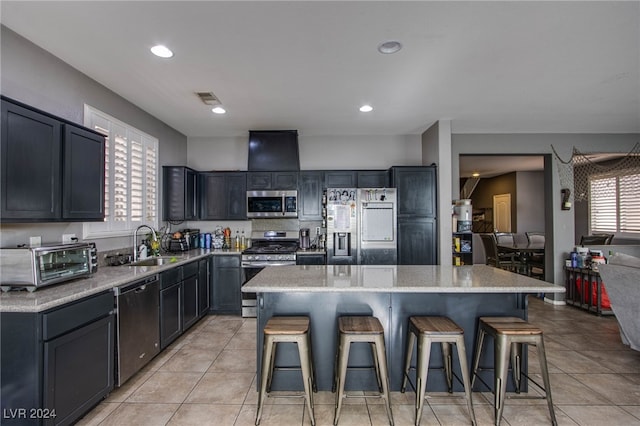 kitchen featuring sink, stainless steel appliances, light tile patterned floors, a breakfast bar area, and a kitchen island