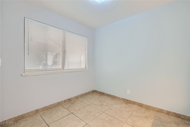 unfurnished room with a textured ceiling and light tile patterned floors