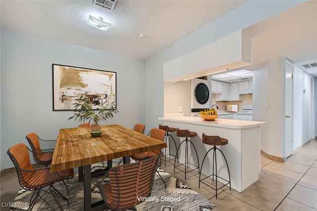 dining room with stacked washer and dryer, a textured ceiling, sink, and light tile patterned flooring