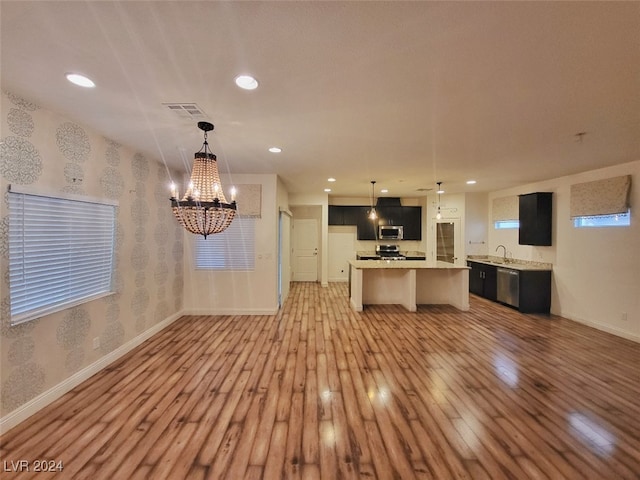 kitchen with a center island, appliances with stainless steel finishes, decorative light fixtures, and light hardwood / wood-style floors