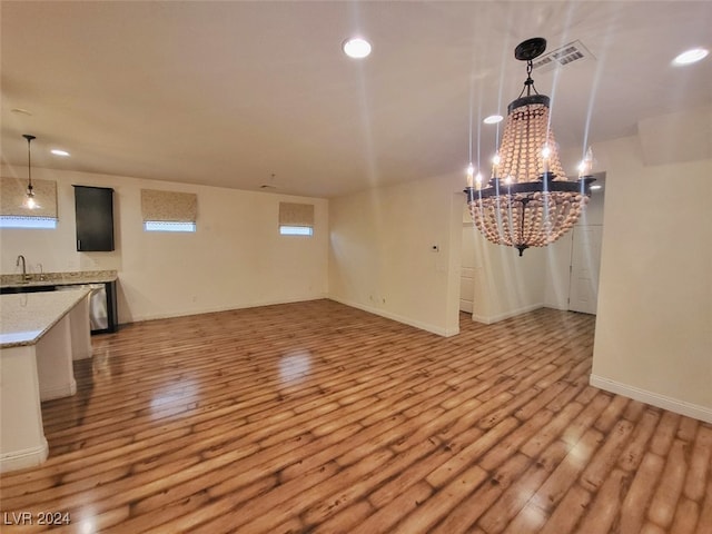 unfurnished dining area with light hardwood / wood-style floors, sink, and a chandelier