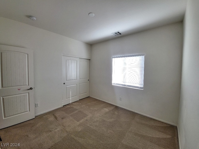 unfurnished bedroom with light carpet and a closet