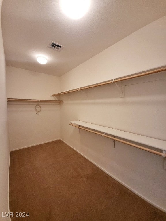 walk in closet with dark colored carpet