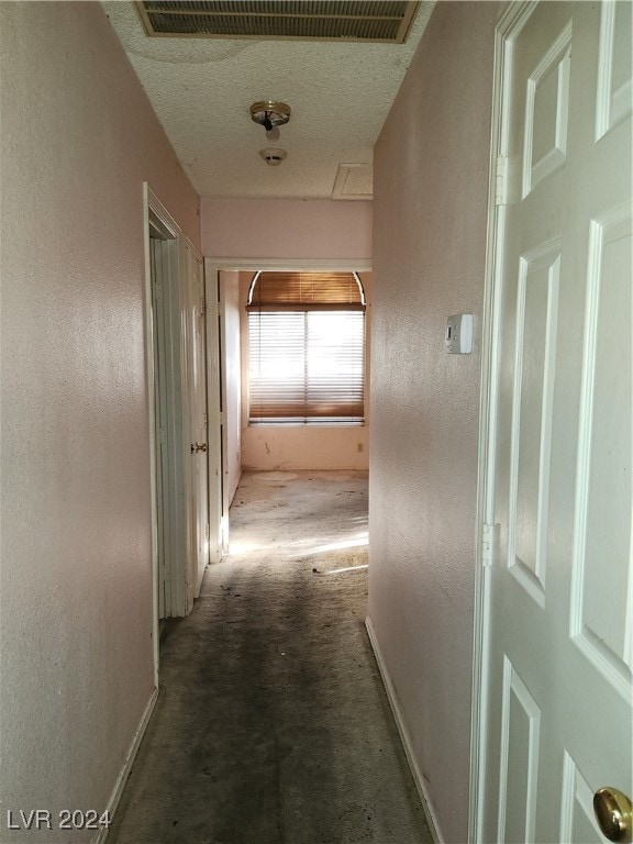 hallway with carpet and a textured ceiling