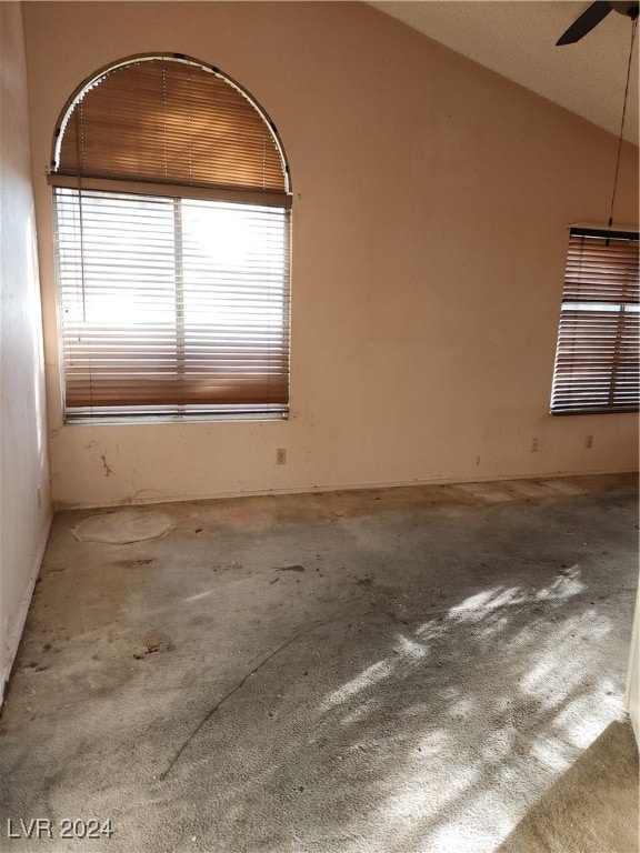 carpeted empty room featuring ceiling fan, a wealth of natural light, and vaulted ceiling