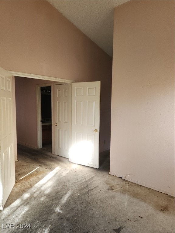 unfurnished bedroom with a closet, carpet flooring, and high vaulted ceiling