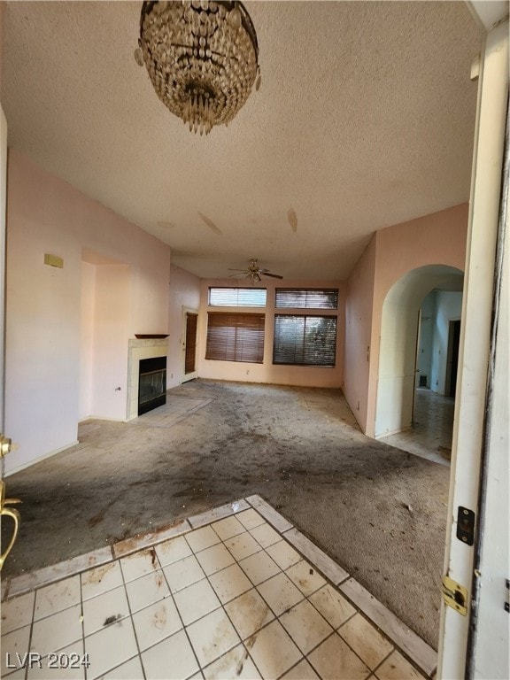 unfurnished living room featuring a textured ceiling, light colored carpet, and ceiling fan