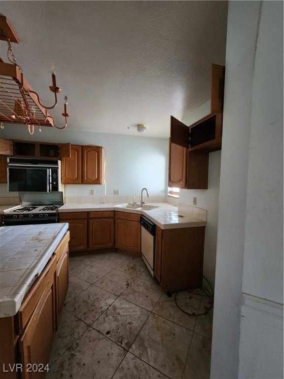 kitchen with black appliances, sink, a textured ceiling, tile counters, and light tile patterned floors