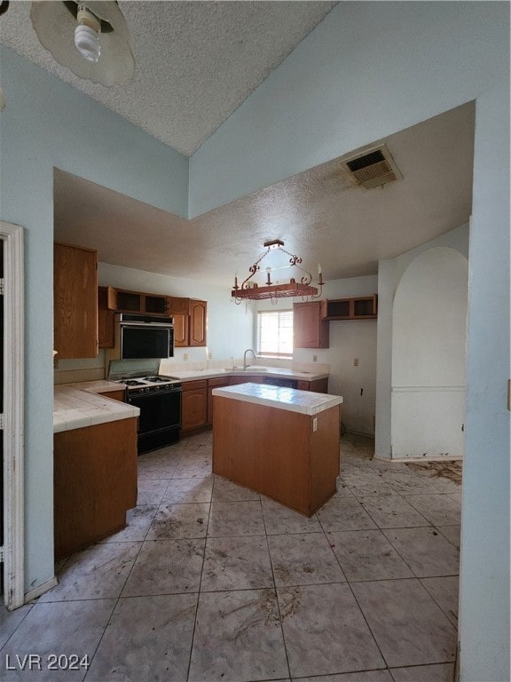 kitchen featuring a kitchen island, ceiling fan, a textured ceiling, vaulted ceiling, and range with gas stovetop