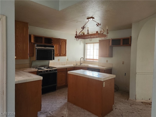 kitchen featuring tile counters, sink, light tile patterned floors, stove, and a textured ceiling