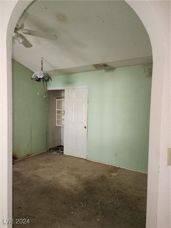 empty room with ceiling fan, a textured ceiling, and concrete flooring