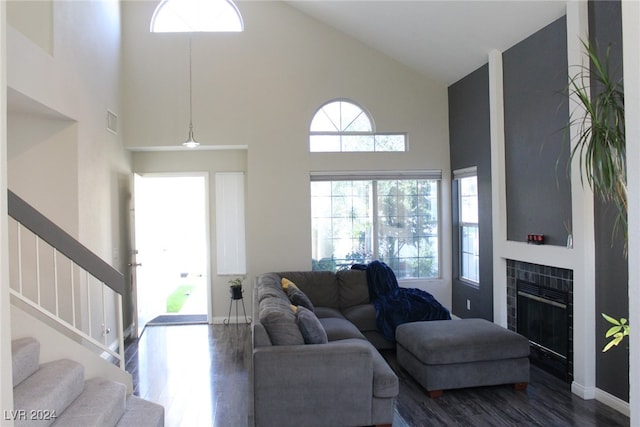 living room with a tile fireplace, high vaulted ceiling, and dark hardwood / wood-style flooring