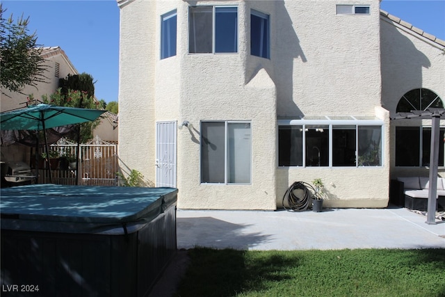 back of property with a hot tub and a patio area