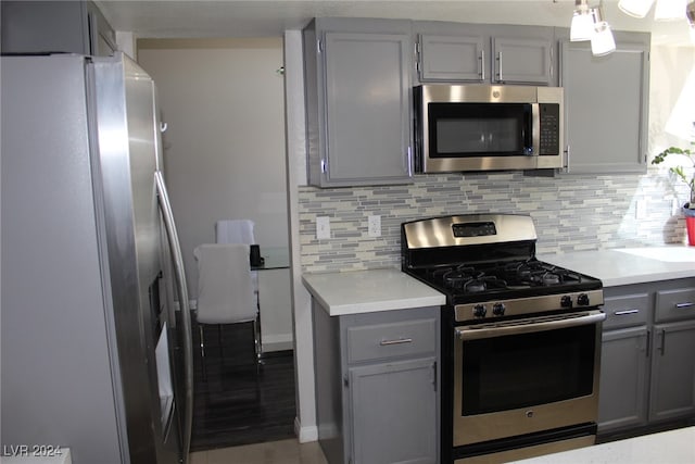 kitchen with appliances with stainless steel finishes, decorative backsplash, gray cabinets, and light wood-type flooring