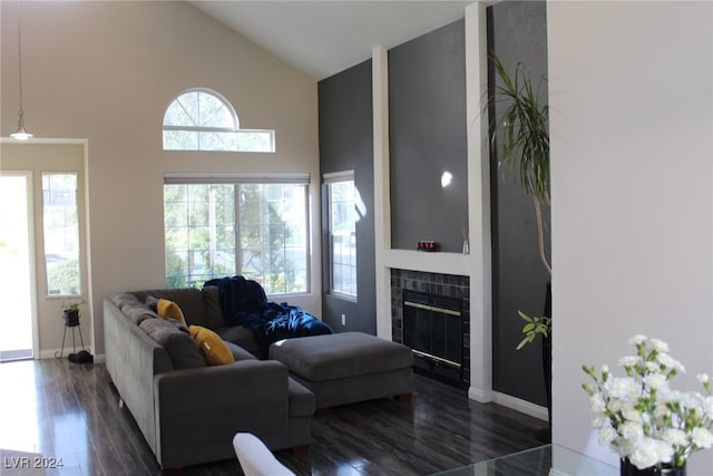 living room featuring a tile fireplace, dark wood-type flooring, and high vaulted ceiling