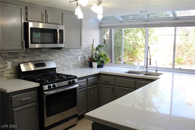 kitchen featuring gray cabinets, sink, appliances with stainless steel finishes, and tasteful backsplash