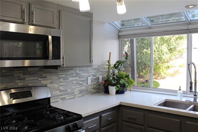 kitchen featuring appliances with stainless steel finishes, tasteful backsplash, sink, and gray cabinets