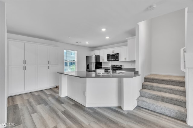 kitchen with a center island with sink, appliances with stainless steel finishes, light wood-type flooring, and white cabinets