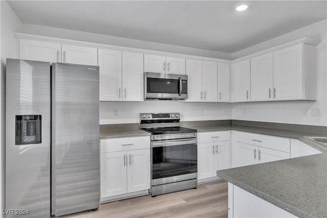 kitchen with stainless steel appliances, light wood-type flooring, and white cabinets