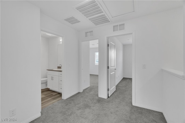 hall with sink and light colored carpet