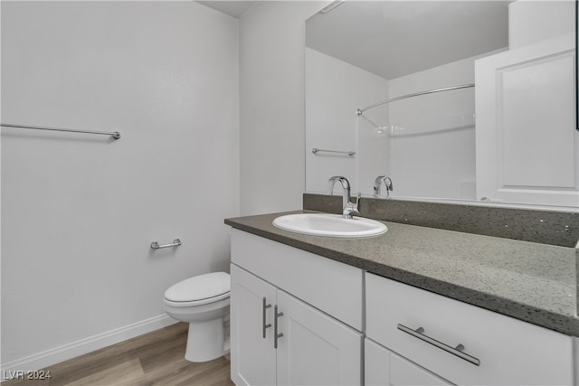 bathroom featuring vanity, hardwood / wood-style floors, a shower, and toilet