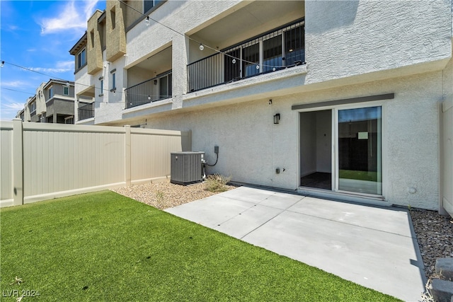 rear view of property with a patio area, a lawn, a balcony, and cooling unit