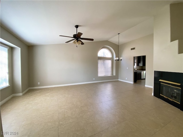 unfurnished living room featuring lofted ceiling and ceiling fan with notable chandelier