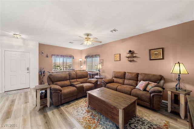 living room with light hardwood / wood-style floors, a textured ceiling, and ceiling fan