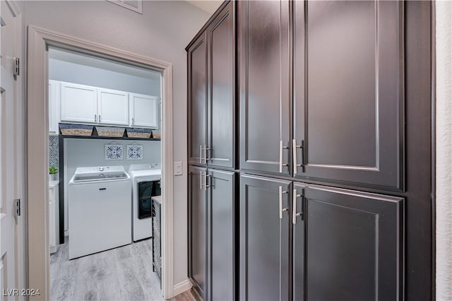 laundry area featuring washer and dryer, light wood-type flooring, and cabinets