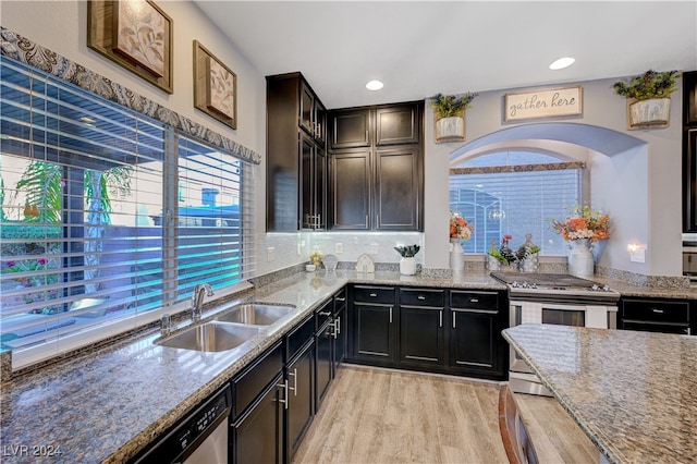 kitchen with sink, light stone counters, stainless steel appliances, and light hardwood / wood-style flooring