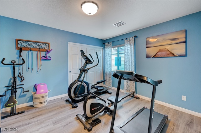 exercise area featuring hardwood / wood-style floors and a textured ceiling