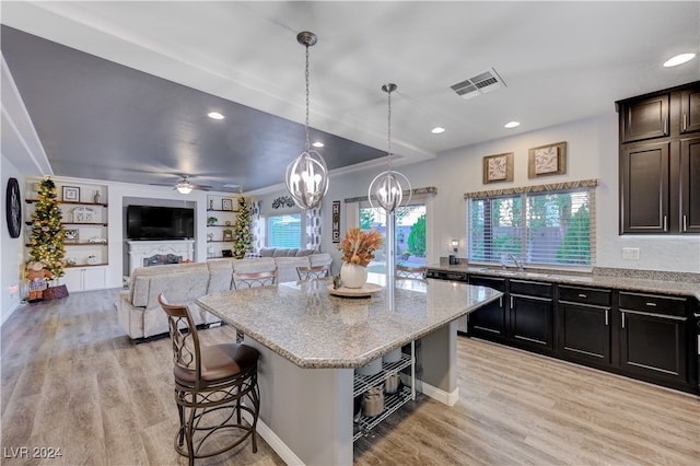 kitchen featuring a center island, a breakfast bar, a healthy amount of sunlight, and hanging light fixtures