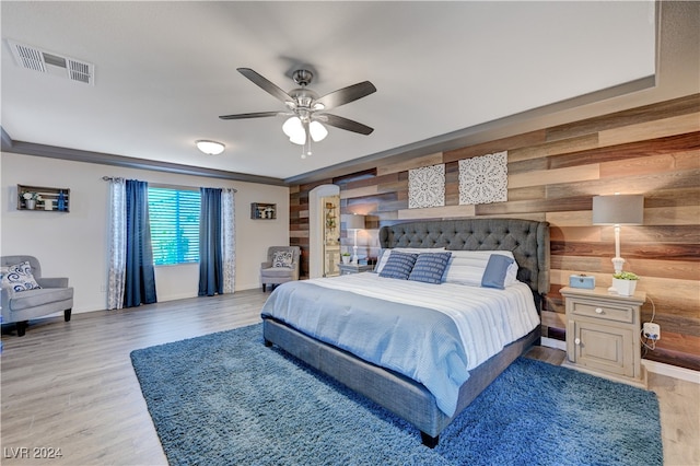 bedroom featuring wood walls, ceiling fan, and light hardwood / wood-style floors