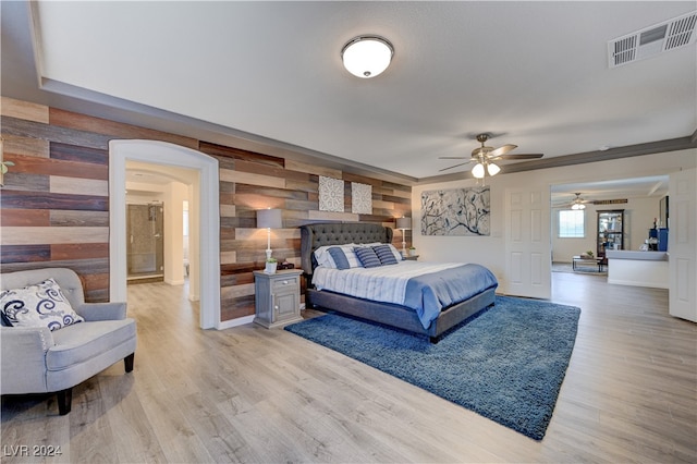 bedroom with hardwood / wood-style flooring, ceiling fan, and wooden walls