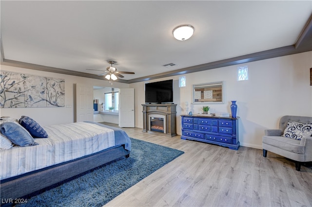 bedroom featuring multiple windows, light hardwood / wood-style flooring, ceiling fan, and crown molding