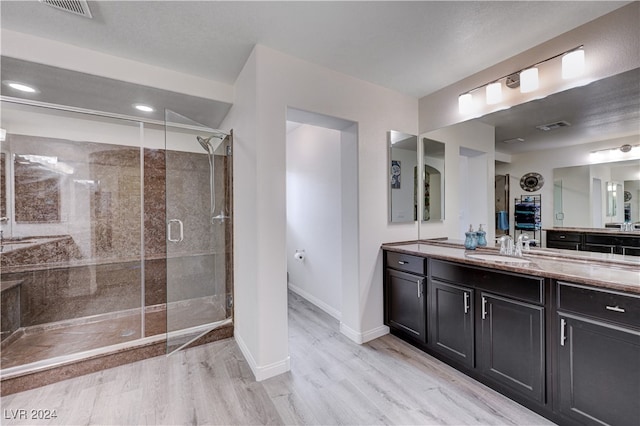 bathroom with hardwood / wood-style floors, vanity, and a shower with shower door