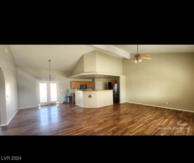 kitchen featuring high vaulted ceiling, stainless steel refrigerator, dark hardwood / wood-style floors, ceiling fan with notable chandelier, and a center island