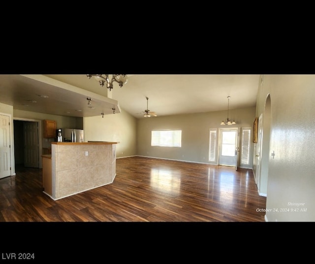 kitchen with lofted ceiling, stainless steel refrigerator, dark hardwood / wood-style flooring, and a chandelier